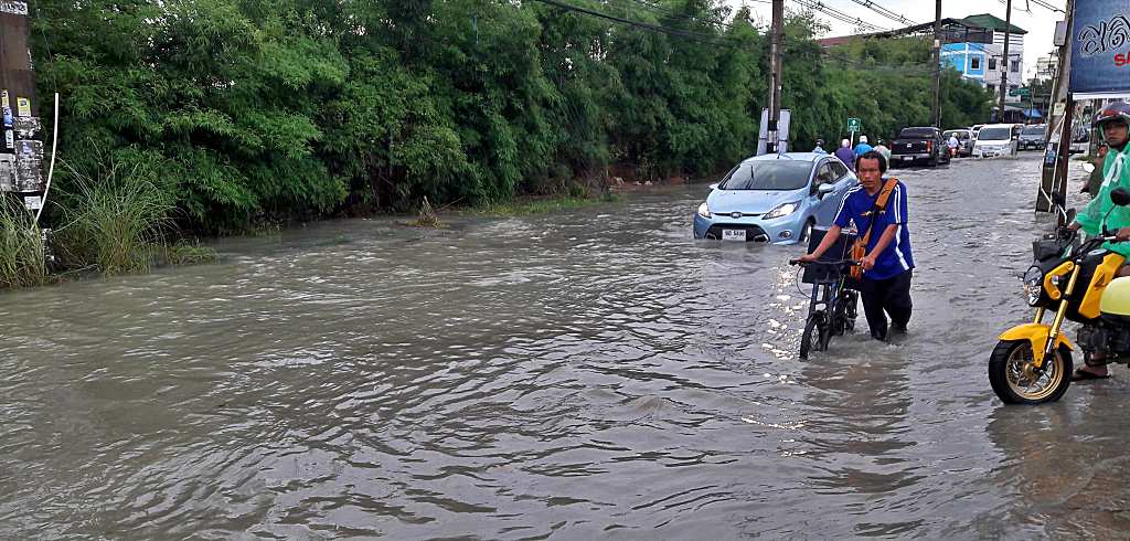 A cyclist and a car negotiating a flooded road in Pattaya