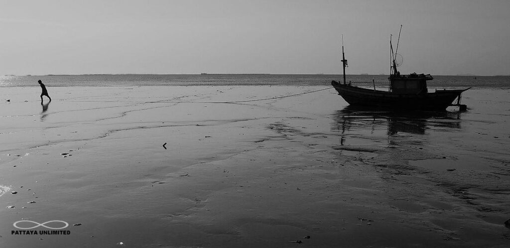 Fisherman and fishing boat silhoutted on Krating Lai beach in Pattaya