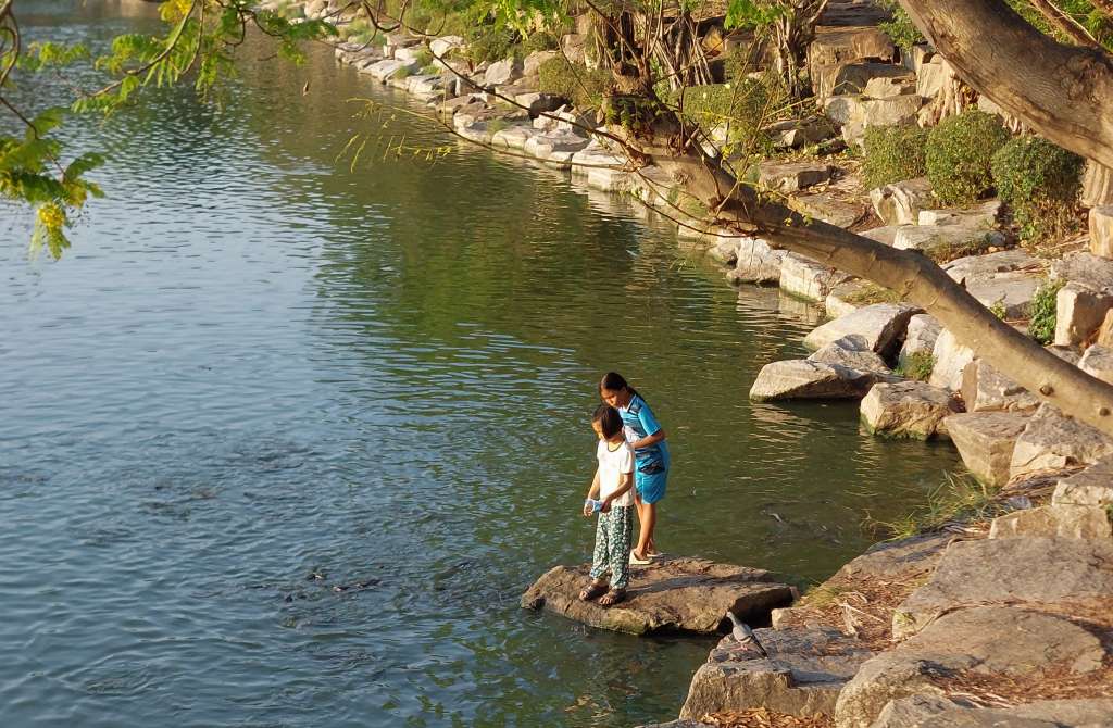 Two girls feeding the fish at Nongprue park