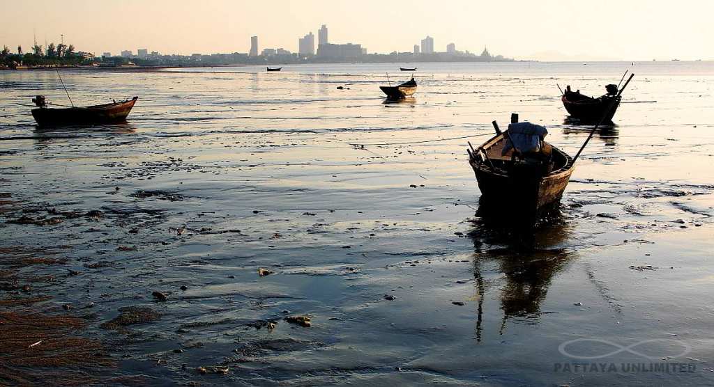 Small wooden fishing boats on Krating Lai beach in Pattaya at low tide